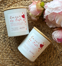 Load image into Gallery viewer, Two 'Amour du Cafe' candles in a white jar on a woven surface with pink flowers.