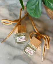 Load image into Gallery viewer, Two small car diffuser bottles with wooden caps in the scent of Autumn in Hell's Canyon, lying on a marble surface.
