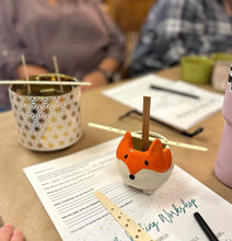 Load image into Gallery viewer, Fox-shaped candle jar on a table with papers and a pen for a candle making class.