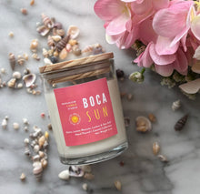 Load image into Gallery viewer, Candle in clear jar with wooden lid in the scent of 'Boca Sun' from Bungalow's Florida Collection sitting on a marble table surrounded by seashells and pink flowers.