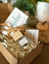 Load image into Gallery viewer, A Bungalow car diffuser in a cardboard box with a decorative bow, attached to a card with the Bungalow Studios logo and a scent description.