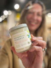 Load image into Gallery viewer, Sue, Bungalow's owner, holding the Spokanite Greenhouse Goddess Candle from the Spring and Summer Collection shown in classic glass 8 oz jar.