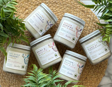 Load image into Gallery viewer, Group of all 6 Seattle Candles in glass jars on a woven mat surrounded by plants and labeld with fall scent names
