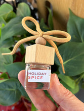 Load image into Gallery viewer, Mini glass jar with wooden lid as a car diffuser in the scent of "Holiday Spice" in front of greenery.