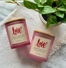 Load image into Gallery viewer, Two frosted pink candle jars laying on their side with a label showing it is the LOVE scent.