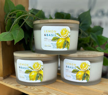 Load image into Gallery viewer, 3 extra-large 24 oz soy candles with wooden lids in the Lemon &. Basil scent, stacked on a display table.