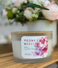 Load image into Gallery viewer, Large candle with a peony label on a wooden table with flowers in the background