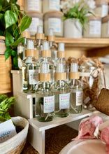 Load image into Gallery viewer, Group of linen sprays in scents from Bungalow's Classic Collection on display at a booth event.