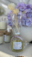 Load image into Gallery viewer, Manito Park High Noon Blooms Reed Diffuser in the Bungalow Spring & Summer Collection in front of purple flowers