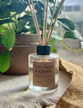 Load image into Gallery viewer, The Palo Santo & Cassis scent in a reed diffuser, showing it in use with wood reeds from the Cascade Collection.