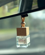 Load image into Gallery viewer, A Bungalow car diffuser in the Peony & Nectar scent hanging from the car rearview mirror.