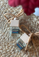 Load image into Gallery viewer, Two small glass bottles car air fresheners with wooden caps labeled 'Spokane River Winter' on a textured woven surface.