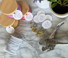 Load image into Gallery viewer, The colorful embossed jar candles are shown with the unique round tags string, and metal hooks.