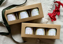 Load image into Gallery viewer, Two cardboard gift boxes with open windows, displaying multiple 3 candles inside. The boxes are presented on a white fabric surface with a green ribbon to the side.
