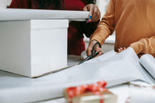 Load image into Gallery viewer, Two people wrapping a gift box.