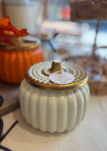 Load image into Gallery viewer, 2 pumpkin shaped candles on a table; one in cream color and one in orange color with gold lids