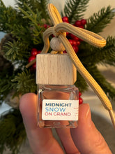 Load image into Gallery viewer, Mini glass jar with wooden lid as a car diffuser in the scent of "Midnight Snow on Grand" in front of greenery.