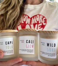 Load image into Gallery viewer, Sue, owner of Bungalow Candle Studio, holding all three California Coast candles from the gift set trio.