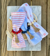 Load image into Gallery viewer, Wood bead napkin rings in use with cloth striped napkins on wooden table.