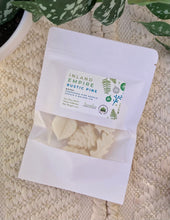 Load image into Gallery viewer, A white pouch of soy wax melts in the Inland Empire Rustic Pine scent laying flat on a woven mat.