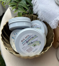 Load image into Gallery viewer, Three round white metal tins with lids labeled 'BIG SKY MONTANA MEMORIES' arranged in a scalloped gold tray on a tabletop, with a white textured cloth and green leaves in the background.
