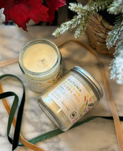 Load image into Gallery viewer, 8oz candle labeled &#39;Autumn Haven on Tubbs Hill&#39; with silver lid on marble surface with pine leaves, red flowers and ribbon surrounding it.
