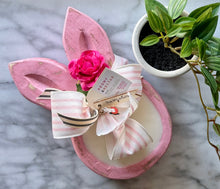 Load image into Gallery viewer, Hand-carved bunny shaped wood dough bowls candle with pink-wash finish, adorned with ribbon, and tagged with scent information for Peony &amp; Nectar.

