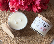 Load image into Gallery viewer, Large candle with wooden lid and 'Cali Glow' candle on a woven surface with pink flowers.
