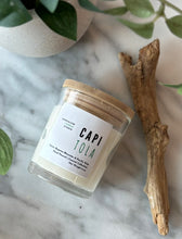 Load image into Gallery viewer, Candles in glass jarsswith wooden lids sit on a marble surface with beachwood and green plan--labeld with the scent of Capitola
