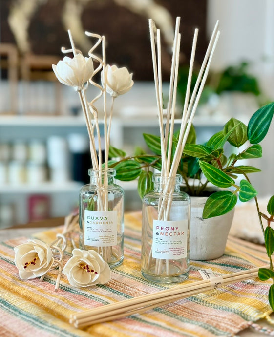 Two scent diffusers from the Classic Collection--one showing the straight wood reeds and the other showing the floral wood reeds