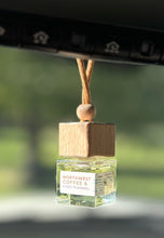 Load image into Gallery viewer, A car diffuser in the Northwest Coffee &amp; Cozy Flannel scent from the Fall Candle Scent Collection hangs from the car rearview mirror.
