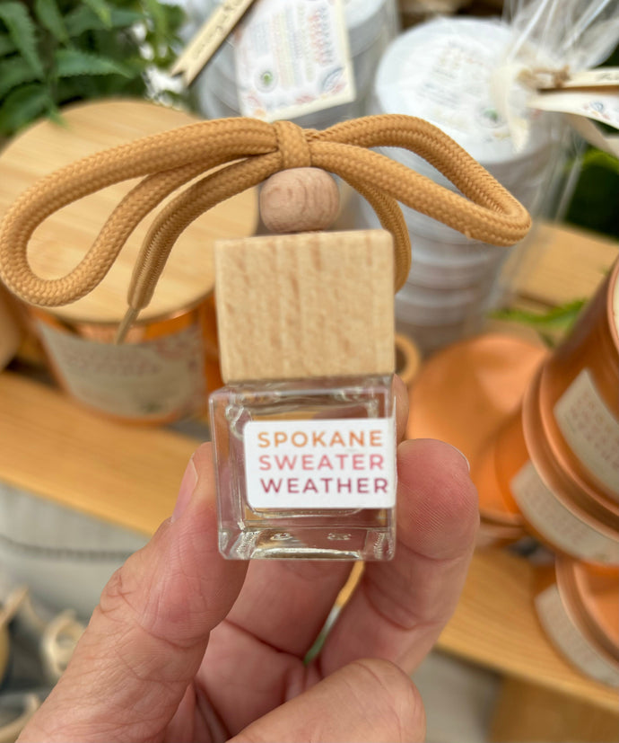 A car diffuser in the Spokane Sweater Weather scent from the Fall Candle Scent Collection being held in a person's hand.