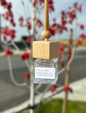 Load image into Gallery viewer, A car diffuser in the Falling For You at Riverfront Park scent from the Fall Candle Scent Collection hangs from the car rearview mirror.
