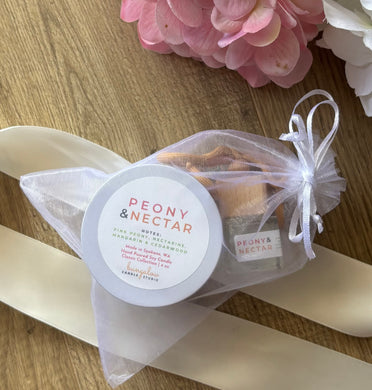 A car diffuser and 4oz mini candle in the Peony & Nectar scent, bundled together in a white mesh drawstring bag.