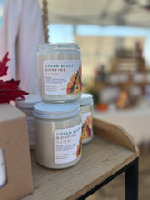 Load image into Gallery viewer, Two candles labeled &#39;Green Bluff Bonfire Glow&#39; on a wooden surface with a blurred background.
