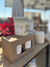 Load image into Gallery viewer, Single candle on top of a boxed duo of candles on shelf with red foliage in background.
