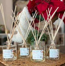 Load image into Gallery viewer, A group of clear glass reed diffusers with natural unbleached wood reeds, displaying various holiday scents such as vanilla peppermint, orange, and cinnamon.
