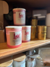 Load image into Gallery viewer, 3 Candles in pink frosted jars stacked on a display case with the label showing it is the LOVE scent
