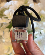 Load image into Gallery viewer, Bungalow car diffuser in the Lavender scent held in front of white flowers.
