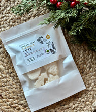 Load image into Gallery viewer, A white pouch of soy wax melts in the Liberty Lake fireside Luxe  scent laying flat on a woven mat.
