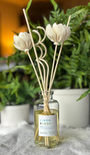 Load image into Gallery viewer, The Linen &amp; Leaf Scent in a reed diffuser from the Classic Collection shown with floral wood reeds.
