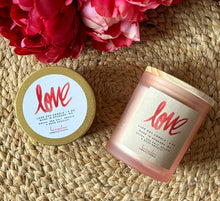 Load image into Gallery viewer, Two Candles with 'love' label and lid on a woven surface with flowers.

