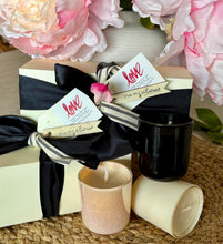 Load image into Gallery viewer, Gift set with three candles and flowers in backgroundon a textured surface
