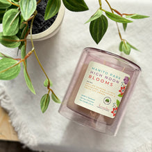 Load image into Gallery viewer, Manito Park High Noon Blooms Candle from the Spring and Summer Collection shown in purple 12 ounce glass jar laying down.
