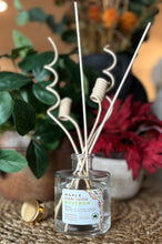 Load image into Gallery viewer, Diffuser in the Maple Chai with Bourbonscent with decorative wood reeds on a table with foliage and flowers in the background
