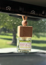 Load image into Gallery viewer, A car diffuser in the Maple Chai with Bourbon scent from the Fall Candle Scent Collection hangs from the car rearview mirror.
