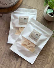 Load image into Gallery viewer, Two White sealed packages with clear windows showing heart shaped Wax Melts in the Lily Leaf Scent, sitting on a wooden table.
