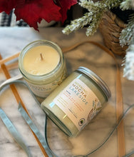 Load image into Gallery viewer, 8oz candle labeled &#39;Morning Mocha Lakeside&#39; with silver lid on marble surface with pine leaves, red flowers and ribbon surrounding it.

