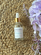 Load image into Gallery viewer, Bottle of Orchid &amp; Vanille scented oil with dropper on a textured surface with a plant in the background
