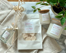 Load image into Gallery viewer, Flat lay of four Bungalow products in the Peony &amp; Nectar scent: 8 oz candle, mini candle, wax melts, and a wood reed diffuser.
